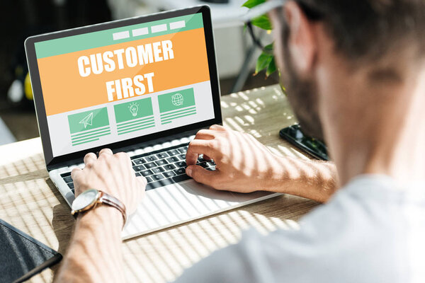 back view of SEO developer using laptop with "customer first" lettering