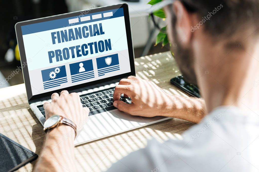 back view of man using laptop with financial protection website