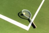 zblízka pohled tenisovou raketu a míček leží na zelený tenisový kurt