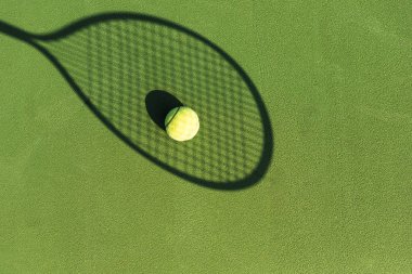 Tenis topu ve yeşil tenis kortunda tenis raketi gölge üstten görünüm