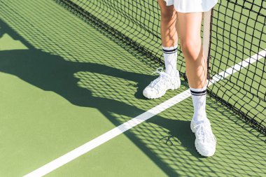 Tenis kortunda net yakın duran kadın tenisçi kısmi görünümü