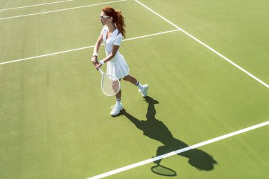 Beyaz tenis kortunda tenis oynamaya Tekdüzen genç çekici kadın yan görünüm