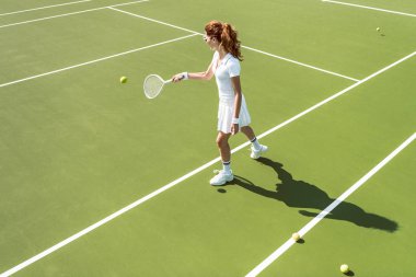 Beyaz tenis kortunda tenis oynamaya Tekdüzen genç çekici kadın yan görünüm