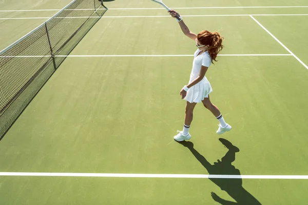 白いテニス コートでテニス制服で若い魅力的な女性の側面図 — ストック写真
