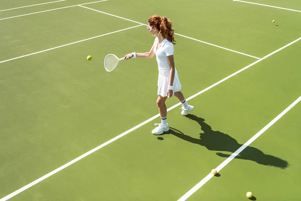 白いテニス コートでテニス制服で若い魅力的な女性の側面図  — 無料ストックフォト