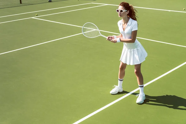 Schöne Frau Weißer Sportbekleidung Und Sonnenbrille Spielt Tennis Auf Dem — kostenloses Stockfoto