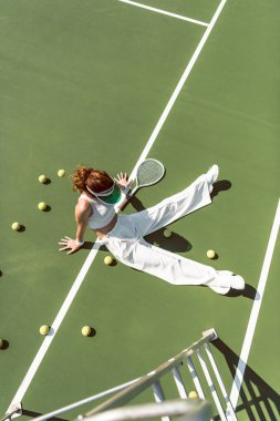 yüksek açı görüntülemek güzel kadının Tenis Kortu top ve raket çevresinde oturan şık beyaz giyim