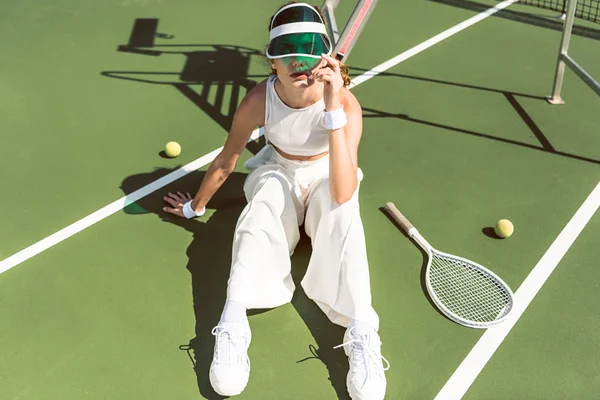 Jonge Vrouw Stijlvolle Witte Kleding Cap Zit Tennisbaan Met Racket — Gratis stockfoto