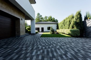 facade of new contemporary house with empty parking, green lawn and garden clipart