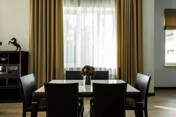 интерьер стильной столовой со столом, стульями и большим окном
