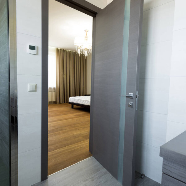 stylish bedroom with bed, view from bathroom door