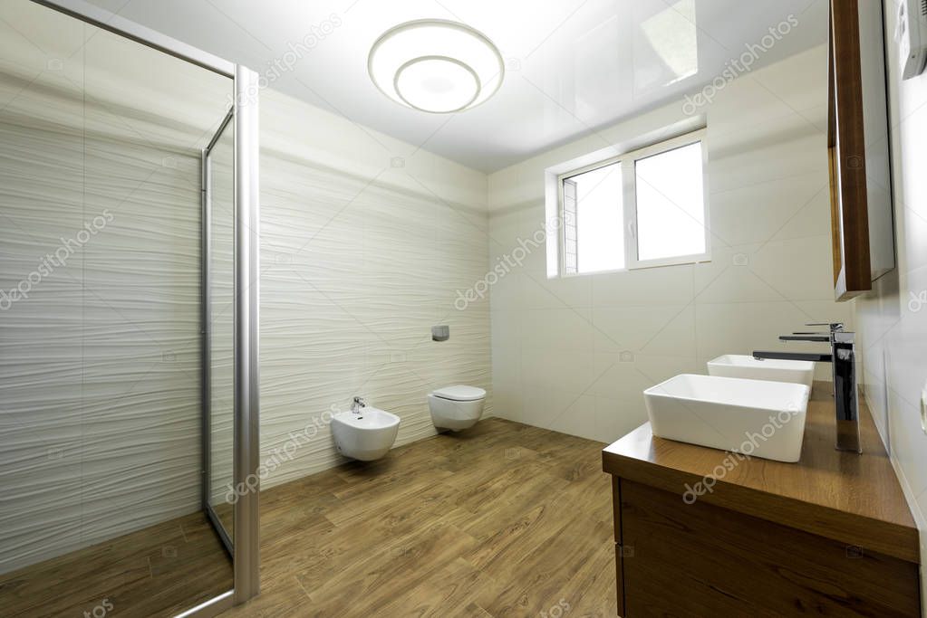 interior of modern bathroom with glass shower, toilet, bidet and two sinks