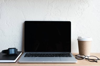 boş ekran, smartwatch, defter, gözlük ve masada kahve ile dizüstü bilgisayar  