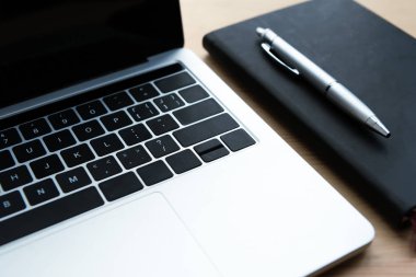 ahşap masa üzerinde laptop, defter ve kalem yakından görmek