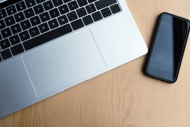 ahşap masa üstünde laptop ve smartphone ile boş perde üstten görünüm 