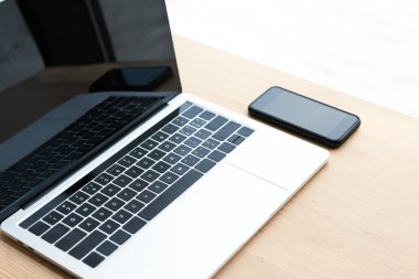 Laptop ve ahşap masa üzerinde boş ekranlar ile smartphone 