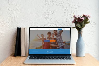 couchsurfing website ekran, kitaplar ve ahşap masa üzerinde Vazoda Çiçekler ile dizüstü bilgisayar