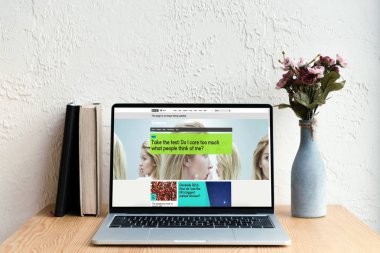 bbc Web sitesi ekran, kitaplar ve ahşap masa üzerinde Vazoda Çiçekler ile dizüstü bilgisayar