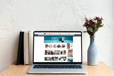 amazon Web ekran, kitaplar ve ahşap masa üzerinde Vazoda Çiçekler ile dizüstü bilgisayar