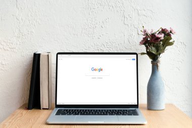 google website ekran, kitaplar ve ahşap masa üzerinde Vazoda Çiçekler ile dizüstü bilgisayar