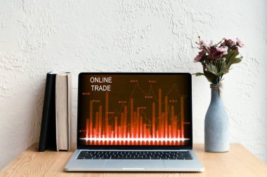laptop ekran, kitaplar ve ahşap masa üzerinde Vazoda Çiçekler online ticaret ile 