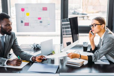 Afrika kökenli Amerikalı işadamı işkadını smartphone ile konuşmak için belgeleri vererek yan görünüm