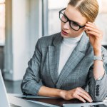 Mujer de negocios en gafas mirando portátil en la oficina