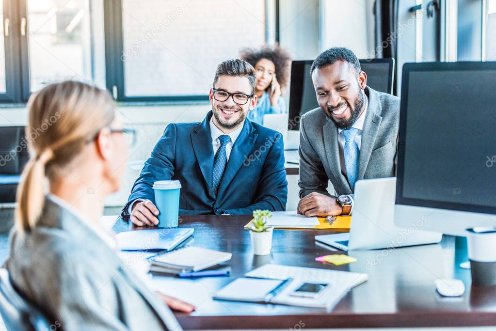smiling multicultural businessmen looking at colleague in office