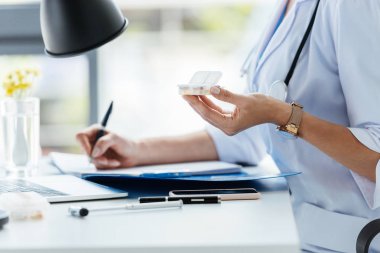 Pano'da yazma ve Office masada hapları tutan kadın doktor kırpılmış görüntü 