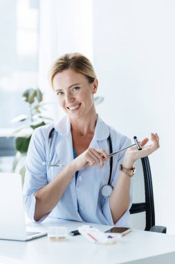 mutlu kadın doktor stetoskop ve ofiste tabloda, refleks çekici ile 