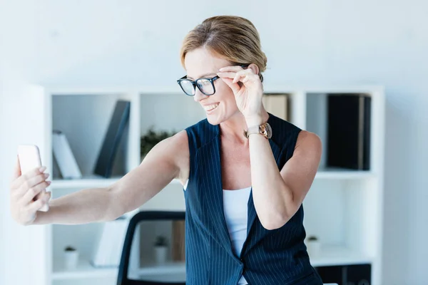 Smiling Businesswoman Eyeglasses Taking Selfie Smartphone Office — Stock Photo, Image