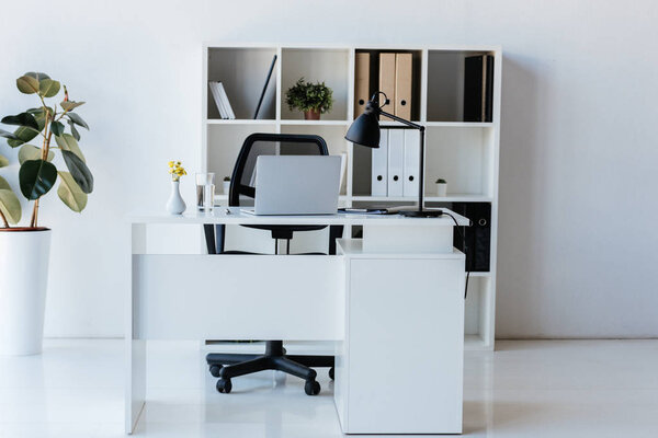interior of modern office with table, laptop and shelves with folders