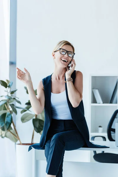 Laughing Businesswoman Eyeglasses Sitting Table Talking Smartphone Office — Free Stock Photo