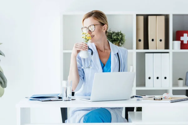 Erwachsene Ärztin Mit Brille Blumen Riechend Tisch Mit Laptop Büro — Stockfoto