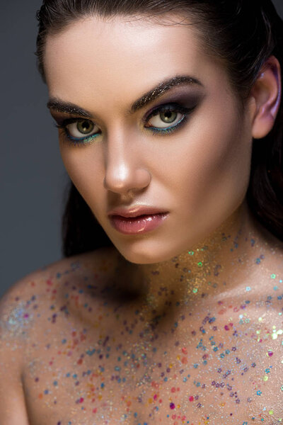 attractive glamorous model posing with glitter on body, isolated on grey