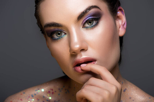 glamorous pensive girl with glitter and makeup, isolated on grey