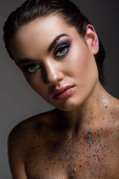 beautiful glamorous girl posing with glitter on naked body, isolated on grey