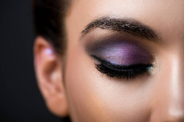 close up of girl with closed eye and glitter eyeshadows, isolated on grey
