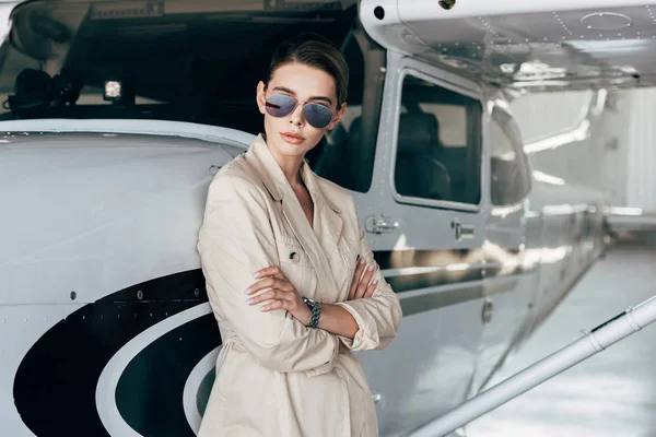 Stylish Young Woman Sunglasses Jacket Posing Crossed Arms Airplane — Stock Photo, Image