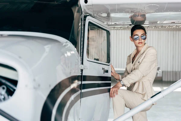 Stylische Junge Frau Mit Sonnenbrille Und Jacke Posiert Flugzeugnähe — Stockfoto