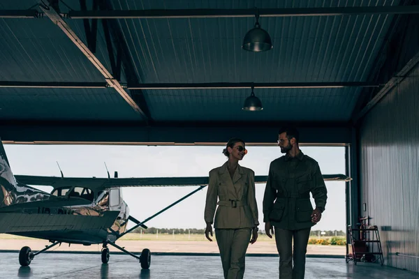 Feliz Elegante Jovem Casal Jaquetas Andando Perto Avião Hangar — Fotografia de Stock