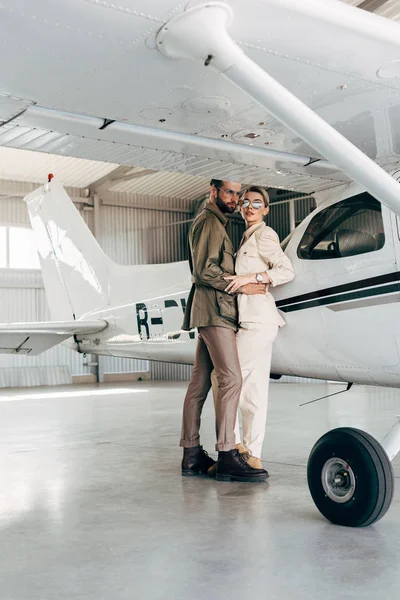 Young Fashionable Couple Jacket Embracing Plane Hangar — Free Stock Photo