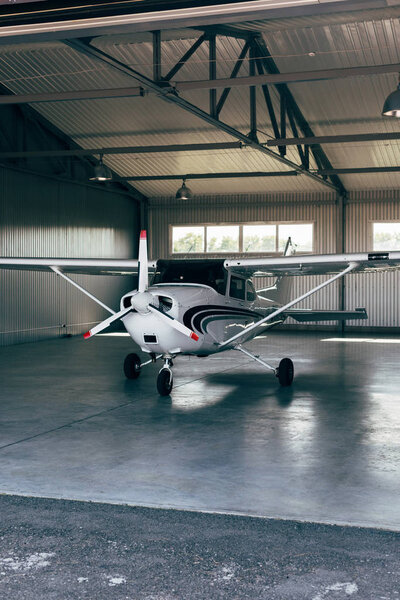 small modern white airplane standing in hangar 