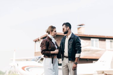 güneş gözlüğü ve birbirine uçak bakarak deri ceketler şık çift yan görünüm 