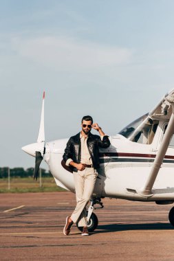 şık erkek pilot deri ceket ve uçak poz güneş gözlüğü
