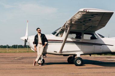 genç moda erkek pilot deri ceket ve uçak poz güneş gözlüğü