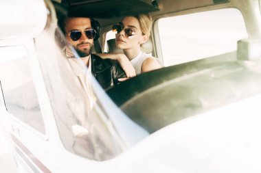 kendine güvenen erkek pilot kulaklık ve kız uçağın kabinde oturan güneş gözlüğü 