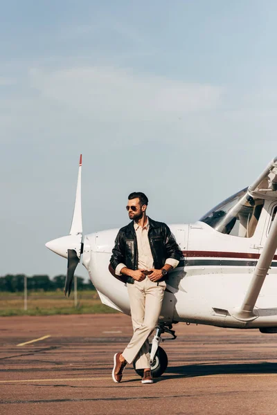 Hombre Guapo Chaqueta Cuero Gafas Sol Posando Cerca Avión —  Fotos de Stock