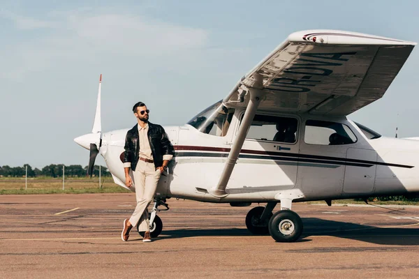 Junger Modischer Männlicher Pilot Lederjacke Und Sonnenbrille Posiert Flugzeugnähe — Stockfoto