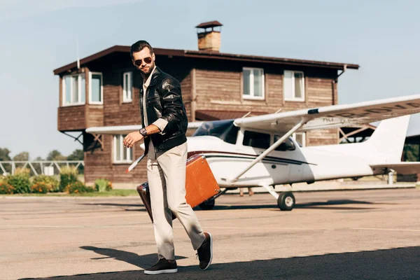 Stilvoller Junger Mann Lederjacke Und Sonnenbrille Spaziert Mit Koffer Flugzeugnähe — Stockfoto